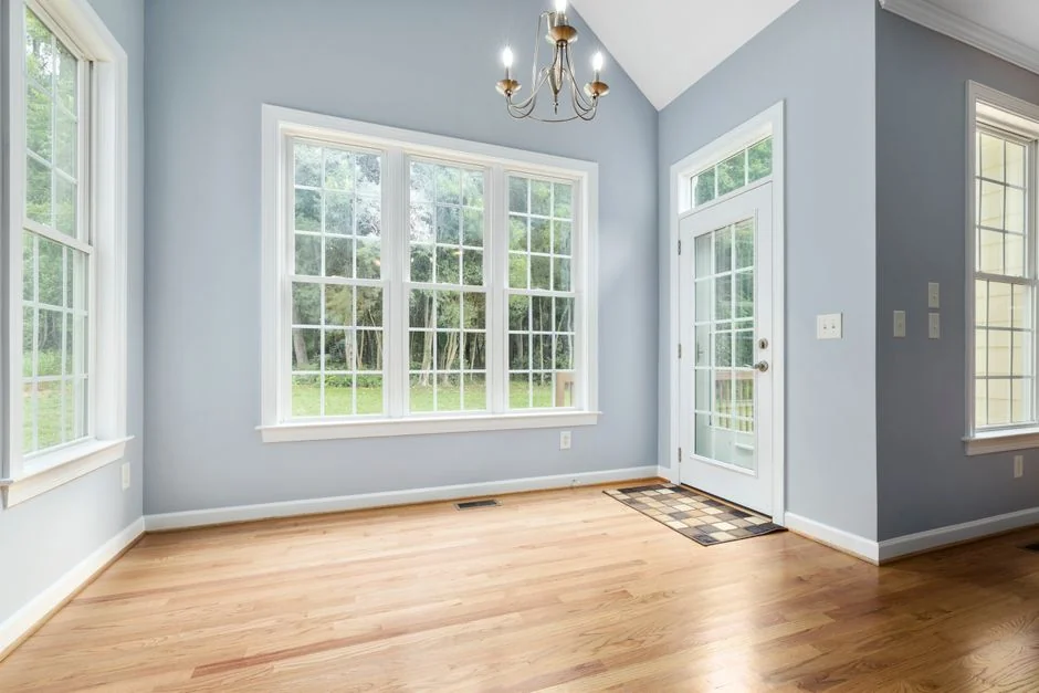 who-we-are Stylish interior with moving boxes labeled Kitchen and Office on a wooden table surrounded by houseplants.